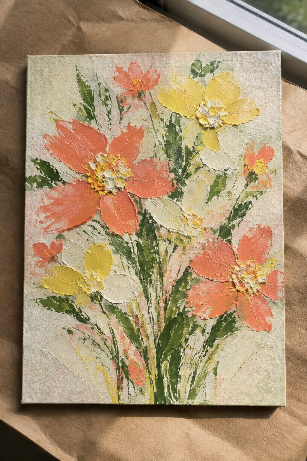 A canvas painting of textured flowers in coral orange, yellow, and white with green stems against a light background.