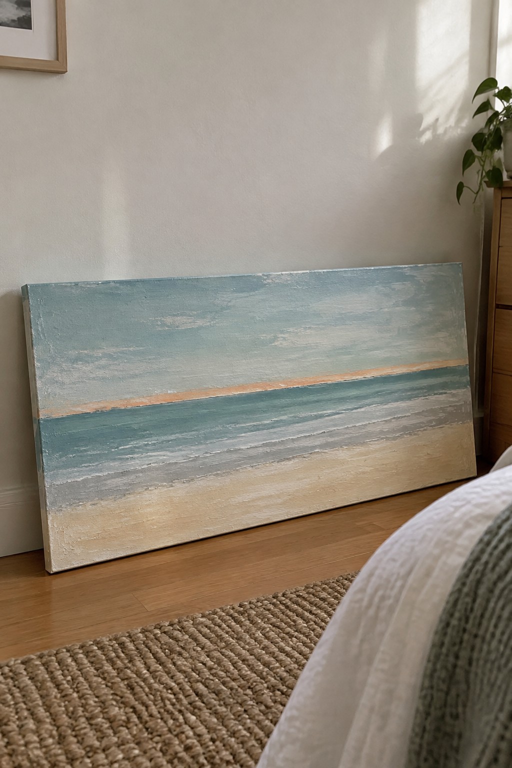 Abstract beach painting with horizontal blue, teal, and sand stripes on wooden floor