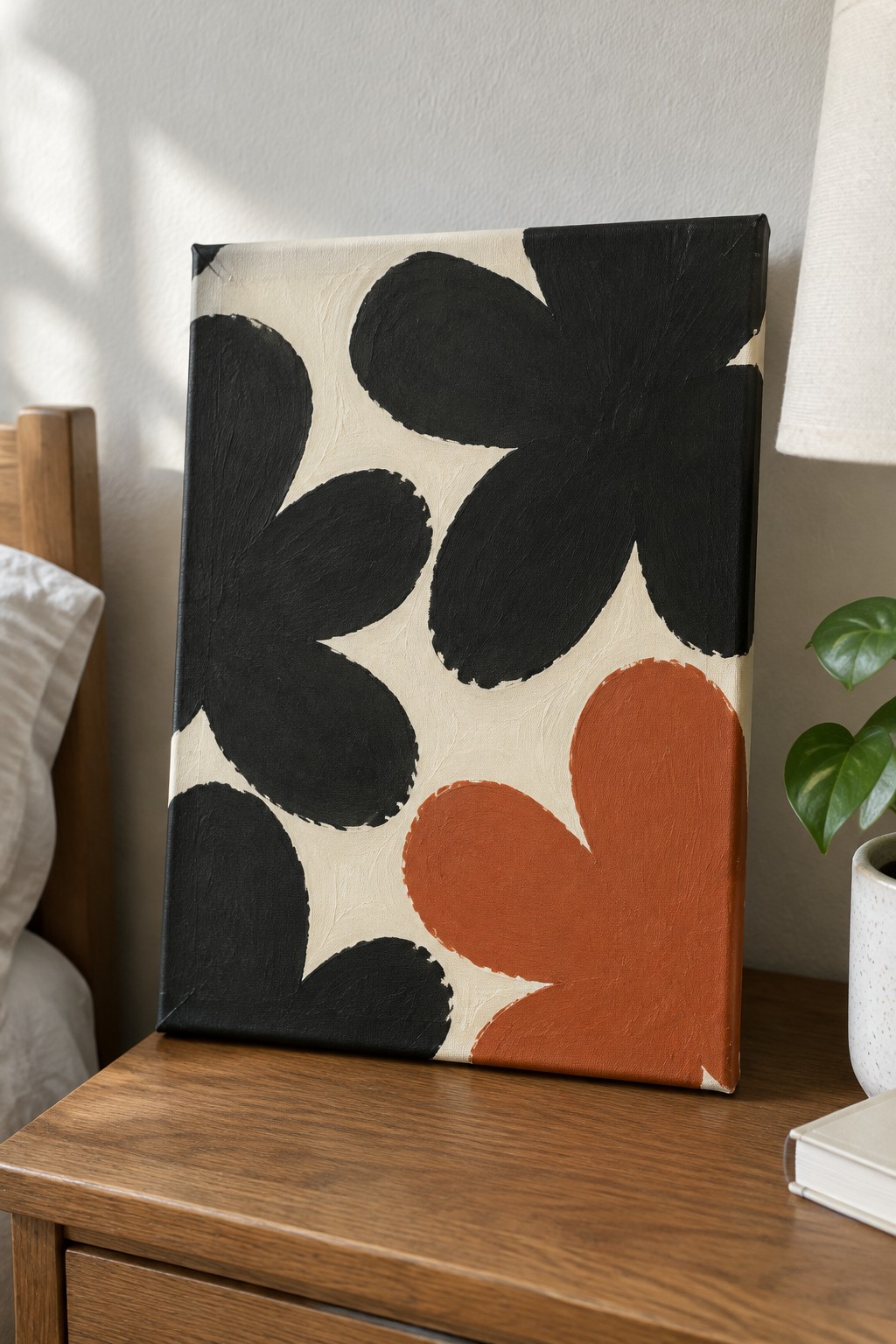 Abstract painting with black and terracotta floral shapes on wooden nightstand