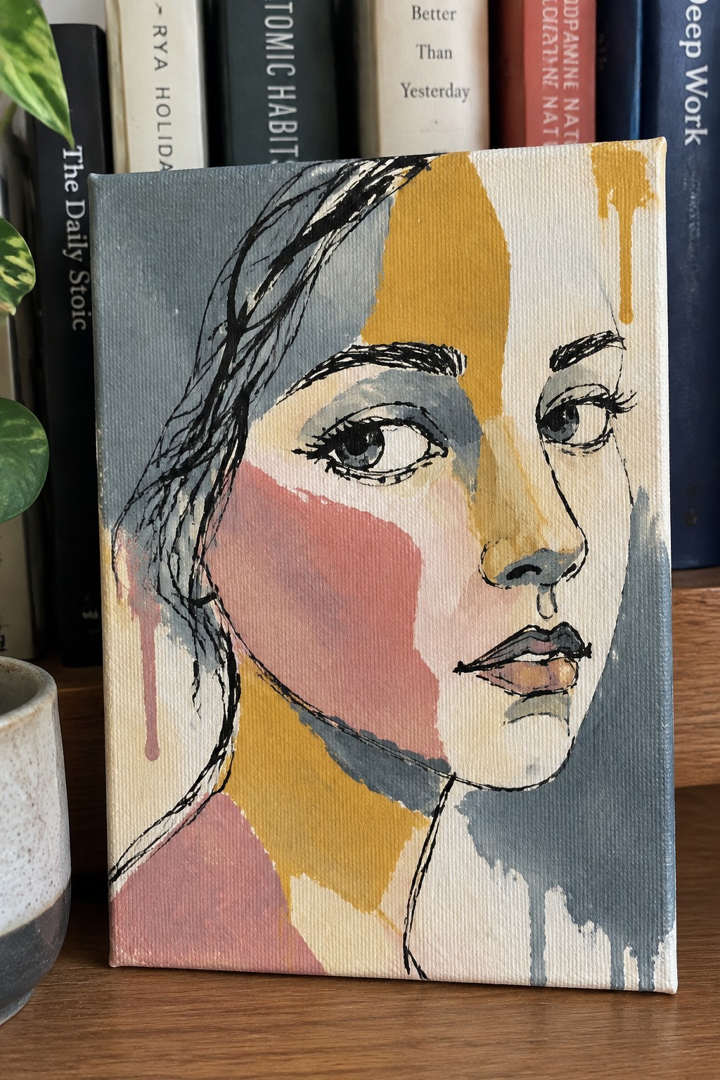 Abstract colorful portrait painting of woman's face on canvas before books