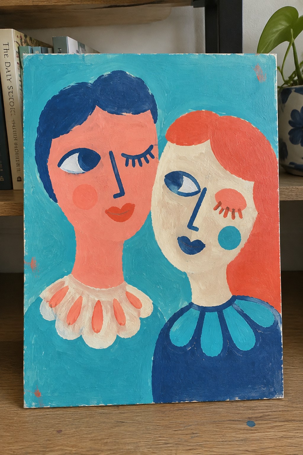 Vibrant abstract painting of two stylized faces with blue and red hair on turquoise.