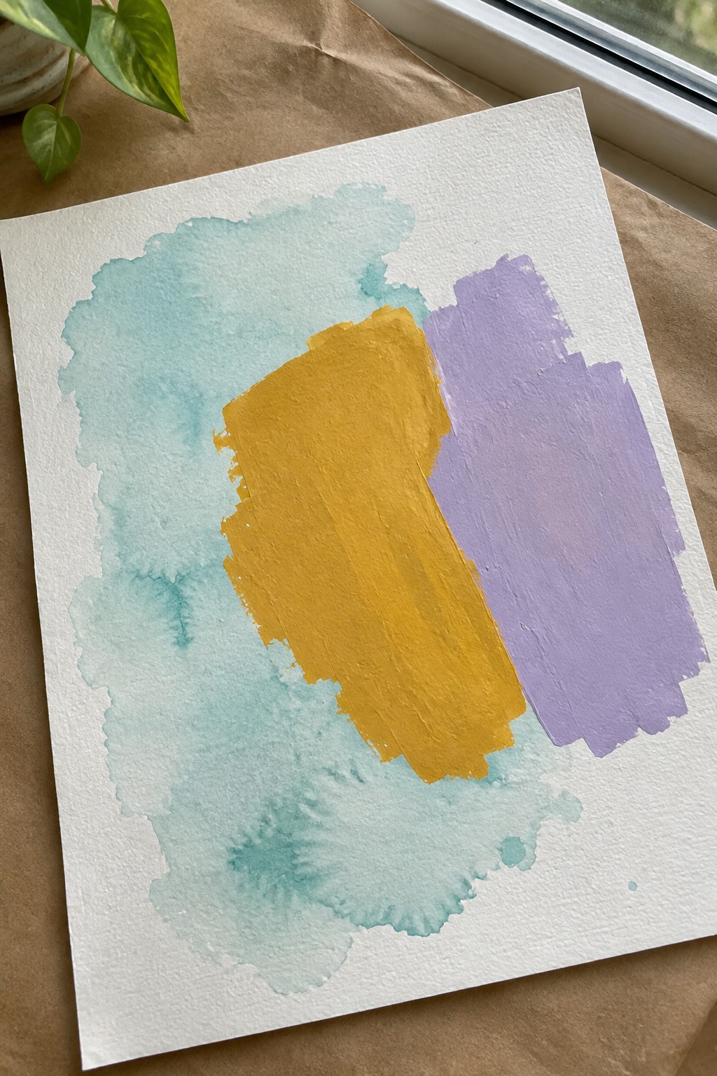 Abstract watercolor on white paper with turquoise wash, yellow and purple strokes near plant and window