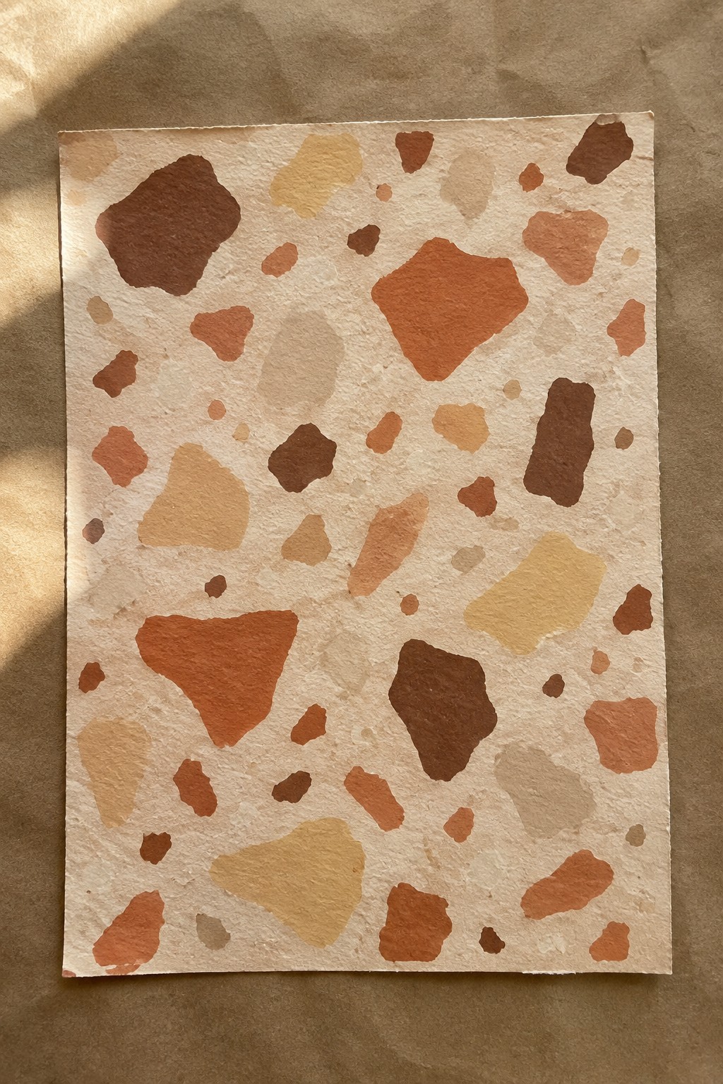 Abstract watercolor shapes in earthy browns and oranges on textured paper.