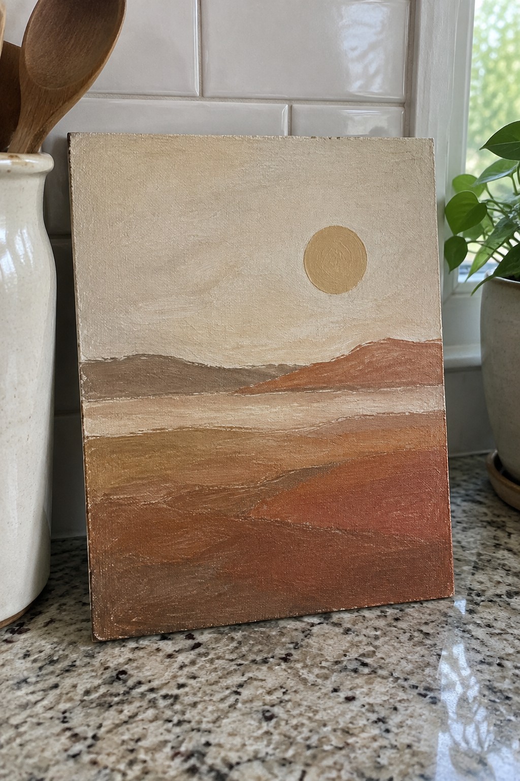 Abstract landscape painting in warm earth tones with gold sun on countertop