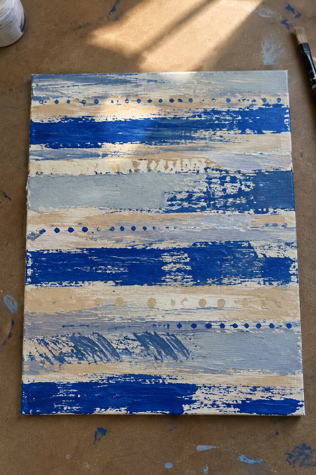 Abstract canvas with blue beige white horizontal stripes dotted lines and textured brushstrokes on paint-splattered surface