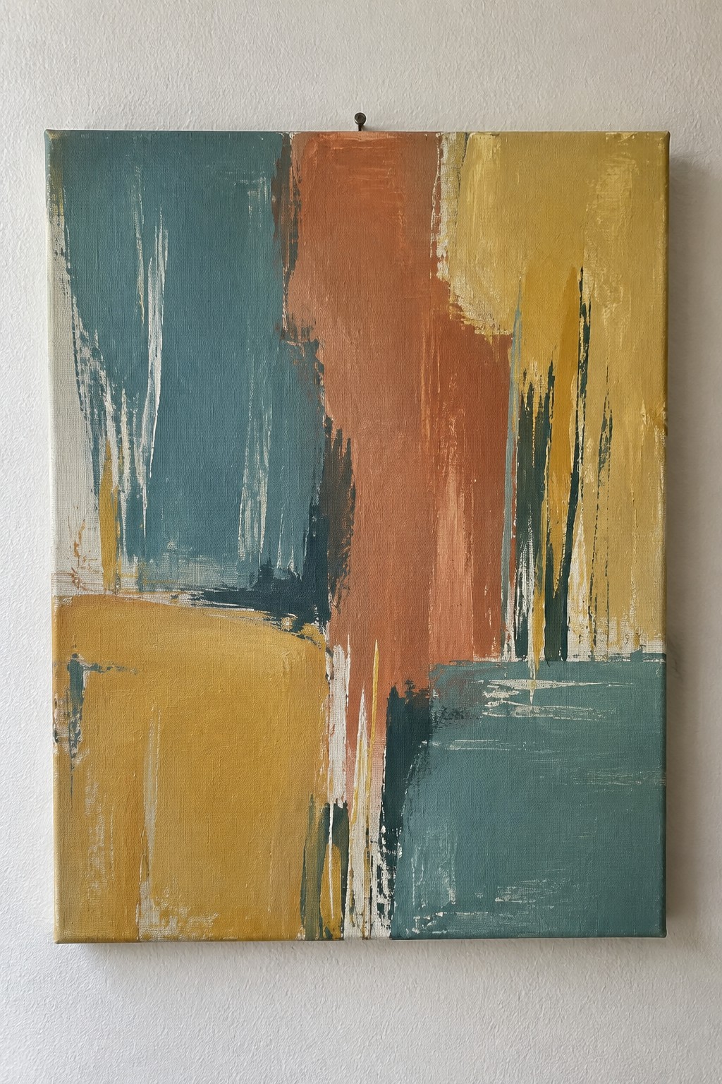 Abstract painting with teal, orange, and yellow brushstrokes on white wall