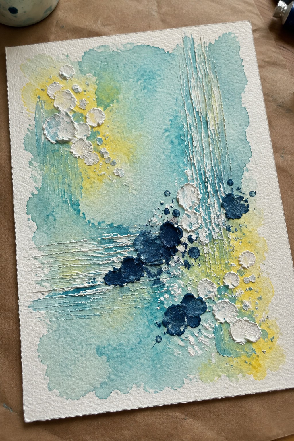 Abstract watercolor with turquoise washes, yellow accents, navy splatters, and textured brushstrokes on paper