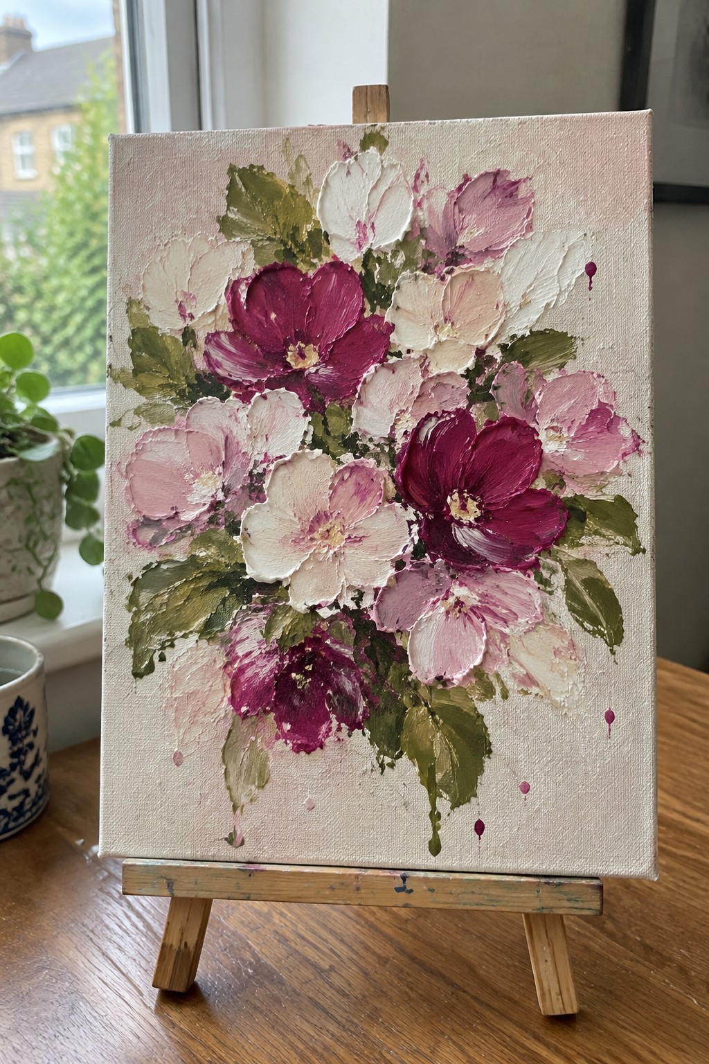 Impasto painting of magenta and pink flowers with green leaves on wooden easel