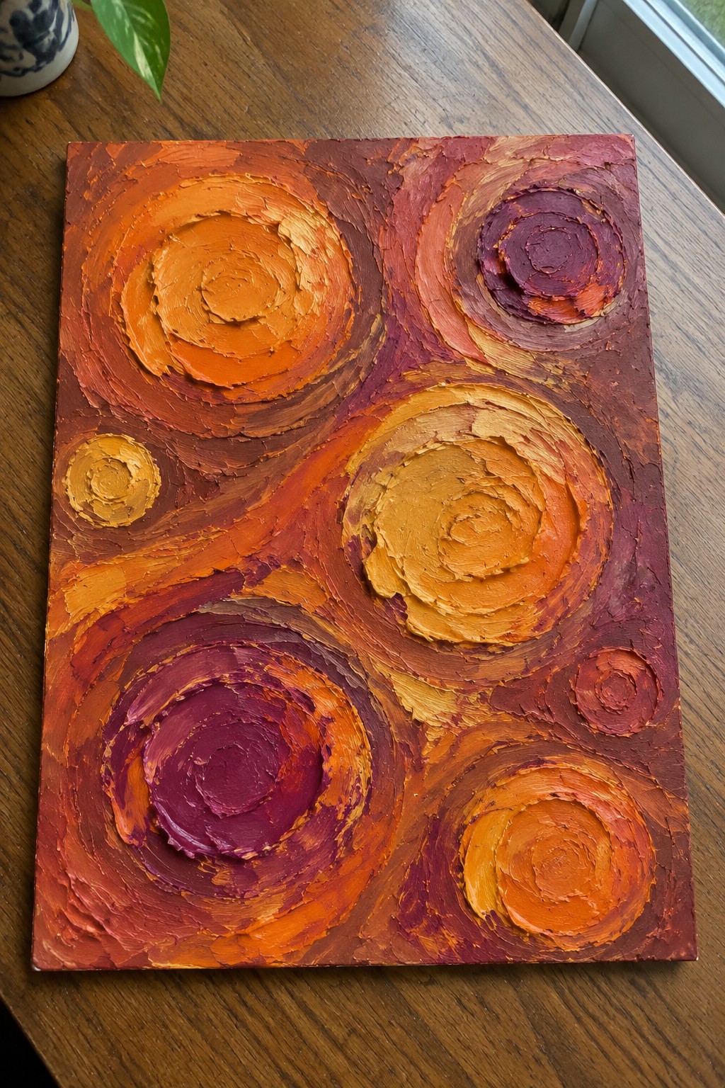 Thick impasto abstract painting with swirling orange red purple yellow circles