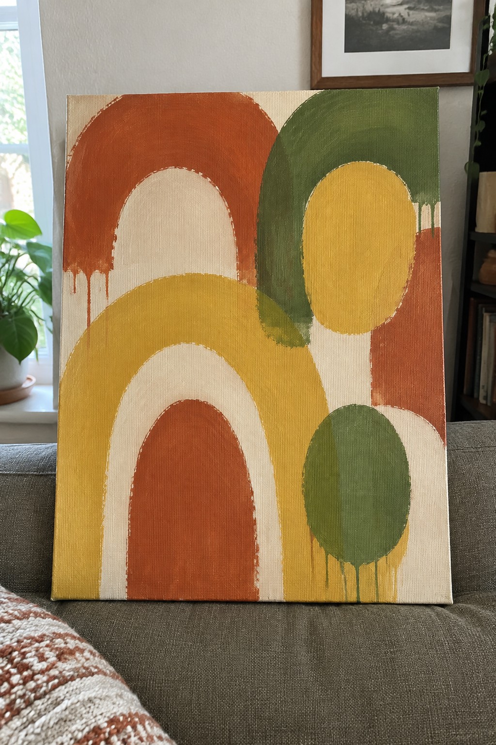 Abstract painting with arches and ovals in orange, yellow, and green on beige canvas.
