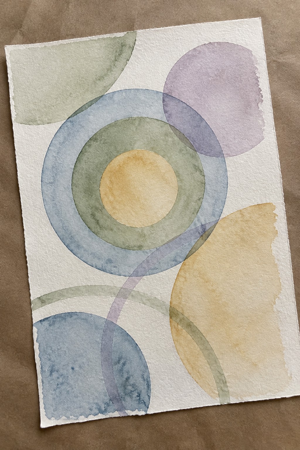 Abstract watercolor with overlapping translucent circles in blue, green, purple, and yellow tones.