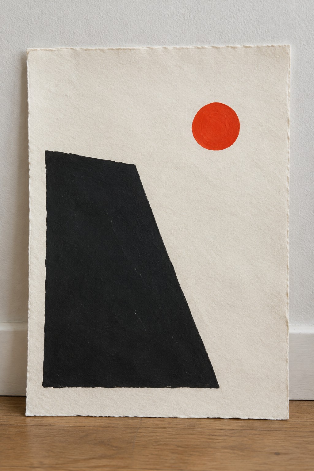 Abstract art with large black shape and small red circle on textured white paper