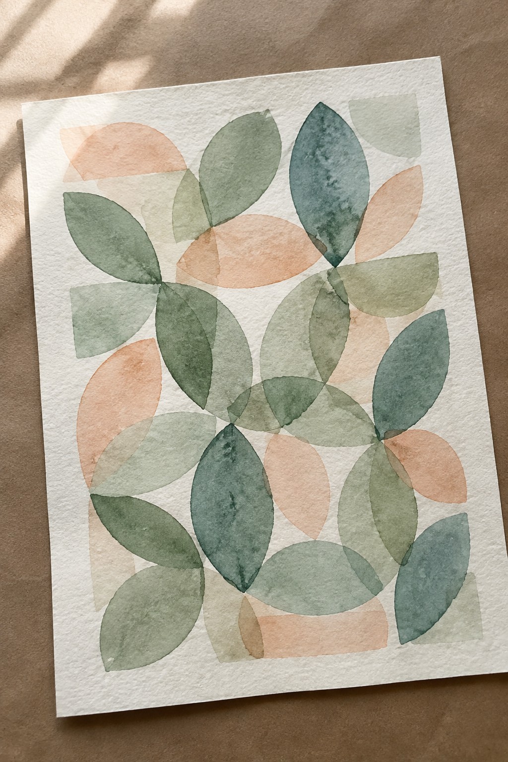Abstract watercolor of overlapping green and peach leaf shapes on white paper.