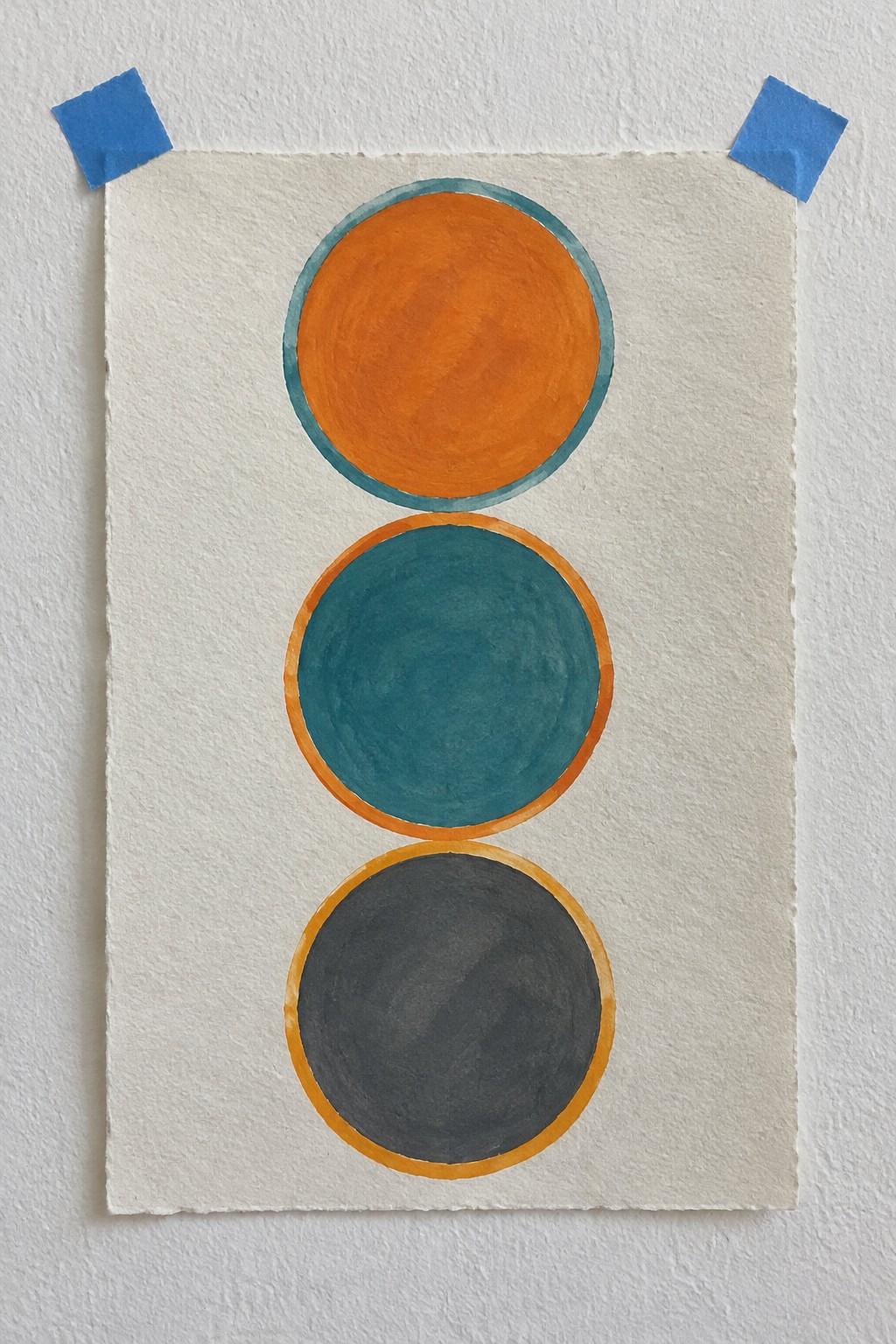 Three painted circles in orange, teal, and gray with borders on taped paper