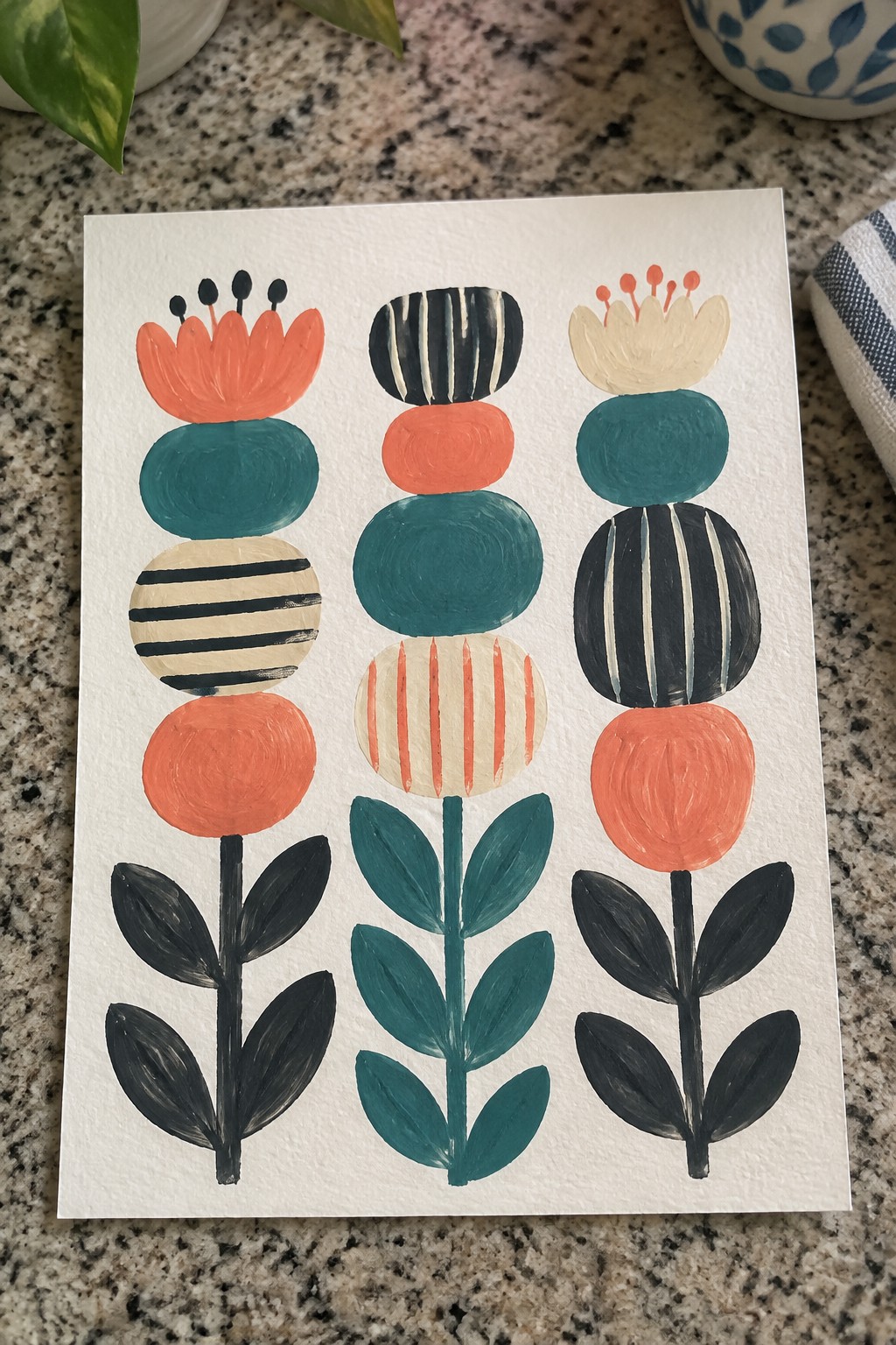 Three abstract flowers with orange, teal, and black patterns on white paper.